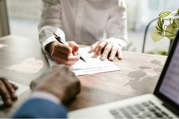 Hands signing a document representing public-private partnership agreements